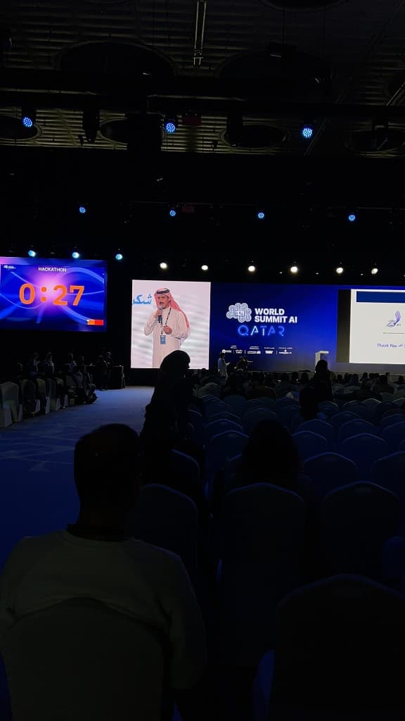 ATF pitch at World Summit AI Qatar, viewed from the auditorium with stage screens and hackathon countdown